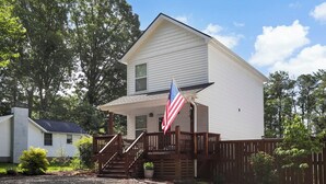 A two-story house with a front porch, a wooden fence, and an American flag. - Mountain View Retreat with Hot Tub,Pet-Friendly,Near Asheville & Biltmore (Arden)