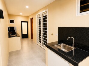 A kitchen with a black countertop, stainless steel sink, and a door with a window.