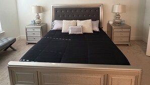 A bedroom with a bed, two bedside tables, a ceiling fan, and a nightstand with a lamp. - Perfect for Nurses-Charming 2-bedroom townhome in Atlanta Metro (Lithonia)