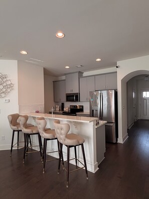 A modern kitchen with a central island, stainless steel appliances, and a bar area with stools. - Perfect for Nurses-Charming 2-bedroom townhome in Atlanta Metro (Lithonia)