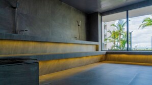 Ein modernes Badezimmer mit Dusche, Badewanne und einem Fenster mit Blick auf Palmen.