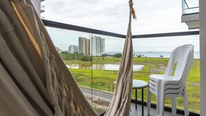Ein Balkon mit Blick auf eine Rasenfläche, ein weißer Plastikstuhl und ein Tisch.