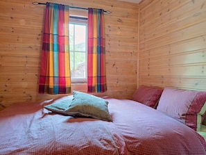 A wooden cabin room with a bed, colorful curtains, and a window. - Bjørnbu by Interhome (Eikerapen)