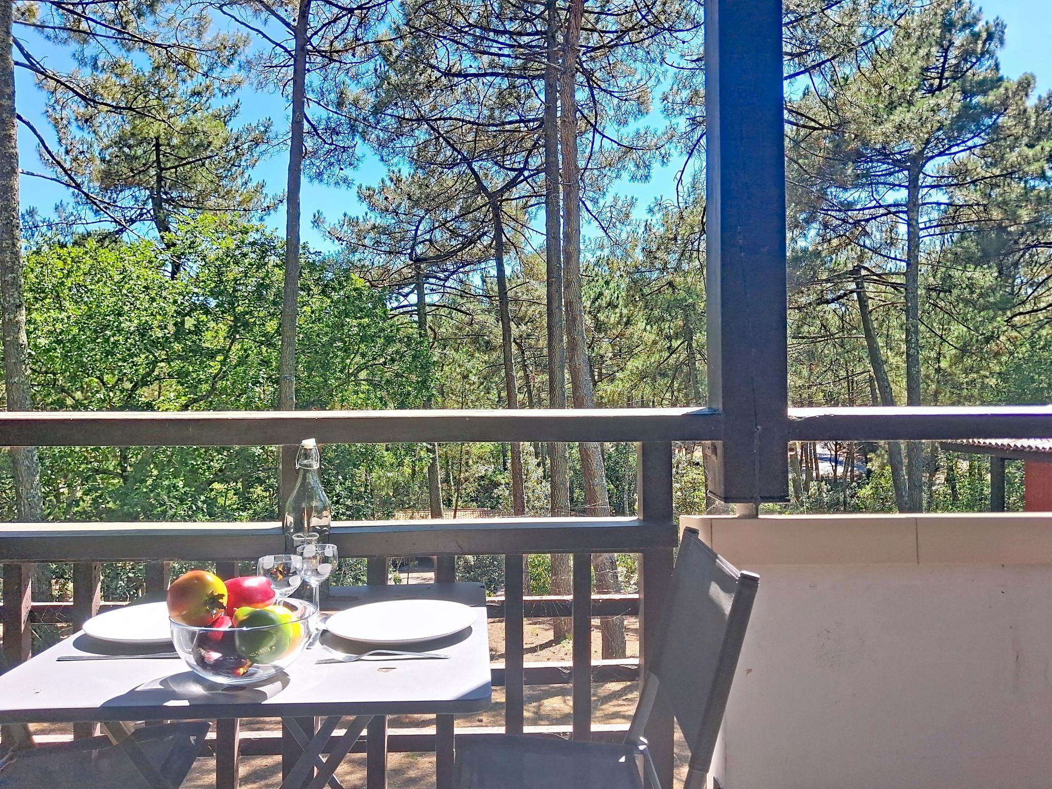 Ein Balkon mit Essplatz, der einen Waldblick bietet.