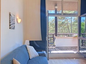 Ein Zimmer mit einer Couch, einer Lampe, einem Gemälde und einem großen Fenster mit Blick auf Bäume.