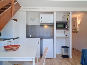 A compact kitchen with a microwave, sink, and a small trash bin. - Les 3 voiles by Interhome (Maubuisson)