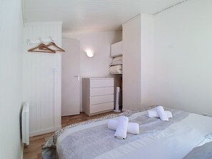 Ein Schlafzimmer mit Bett, Kommode, Kleiderschrank und Wandheizung.