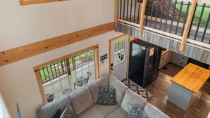 A spacious living area with a sectional sofa, a wooden coffee table, and a view of a tree through a large window.