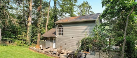 A two-story house with a covered patio area, surrounded by trees.