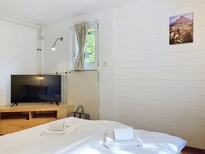 A hotel room with a bed, a TV, a window with curtains, a radiator, and a painting on the wall. - Chalet Chaudoudoux - Les Paccots by Interhome (Les Paccots)