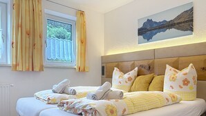 Un letto matrimoniale con lenzuola a motivi floreali, una testiera in legno e un quadro raffigurante un paesaggio appeso al muro.