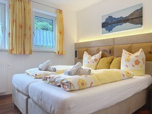 A double bed with floral bedding, a headboard with a wooden panel, and a framed landscape painting on the wall. - Ferienhaus Gundi by Interhome (Pettneu am Arlberg)
