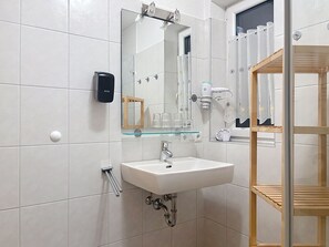 Een badkamer met een witte wastafel, spiegel en handdoekrek.