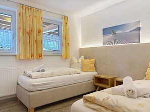 A hotel room with two beds, a window with curtains, a radiator, and a wall-mounted picture. - Ferienhaus Gundi by Interhome (Pettneu am Arlberg)