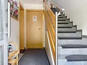 A staircase with a handrail, a wooden door with a no-smoking sign, and a wicker shelf with brochures. - Ferienhaus Gundi by Interhome (Pettneu am Arlberg)
