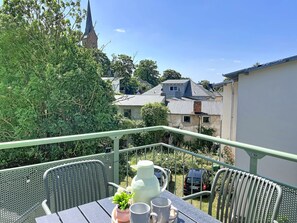 A balcony with a table, chairs, a potted plant, and a kettle. - Dünenklang by Interhome (Zinnowitz)