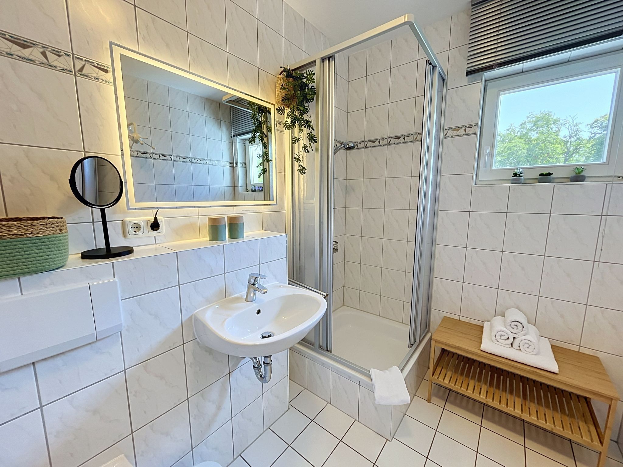 A modern bathroom with a white sink, mirror, and shower.