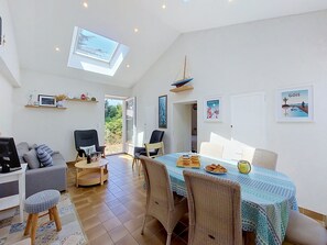 A spacious living area with a dining table, chairs, a sofa, a TV, and a ceiling light. - Villa La Coquille by Interhome (Ile de Noirmoutier)