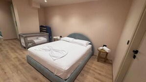 Una habitación de hotel con una cama, una mesita, un banco y una puerta.