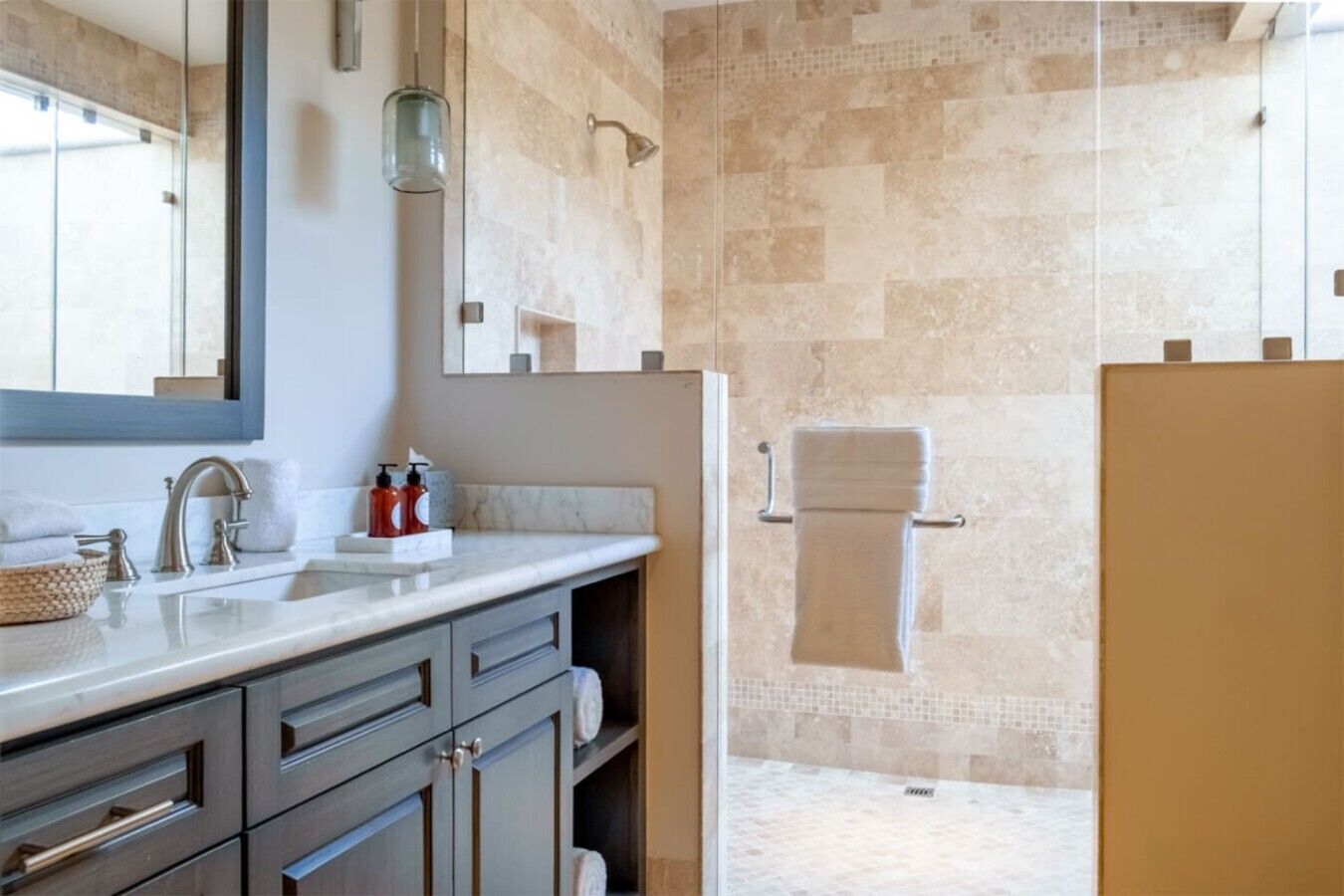 A bathroom with a marble sink, a glass shower enclosure, and a towel rack.
