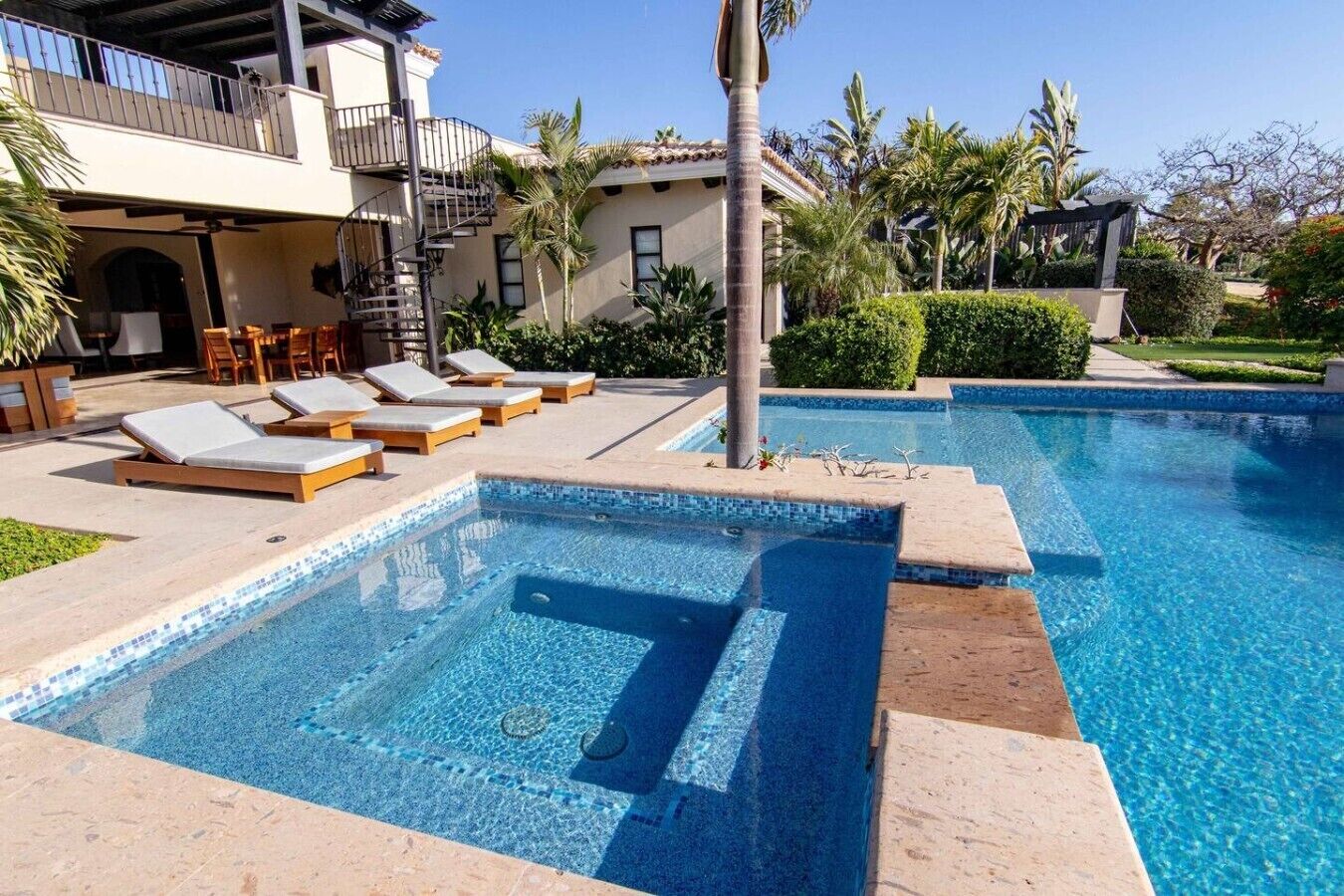 A swimming pool with lounge chairs and a covered seating area.
