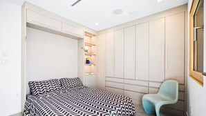 A bedroom with a bed, a chair, and built-in storage cabinets. - Award-Winning Eco Retreat with Fresh Air - certified Passive House (Los Angeles)