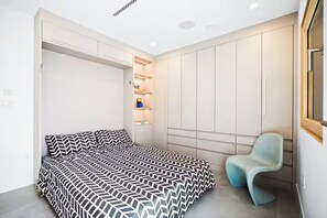 Ein Schlafzimmer mit einem Bett, einem Sessel und Einbauschränken.