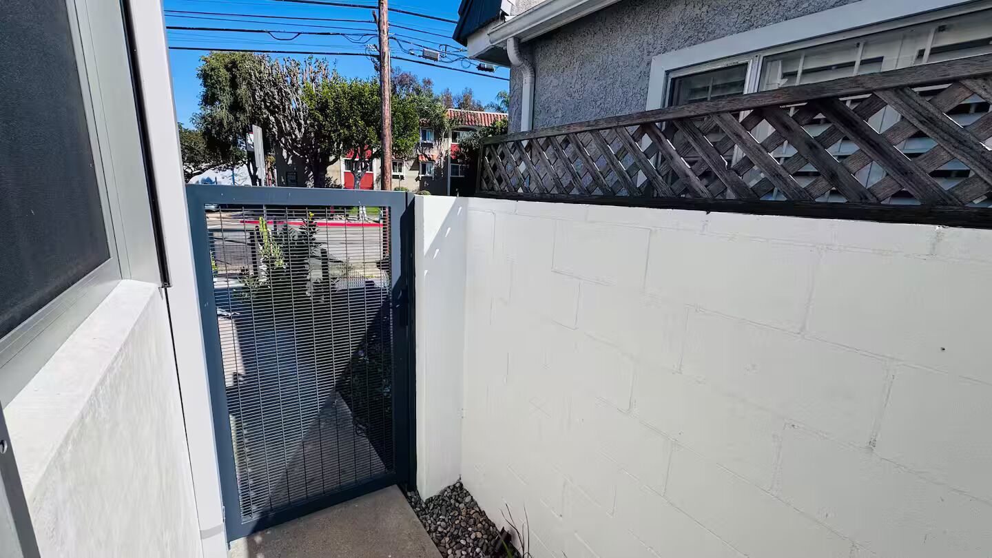 Pared blanca con una reja de metal y una valla de madera.
