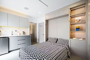 Ein modernes Schlafzimmer mit Bett, Einbauschrank und einer Küchenzeile.