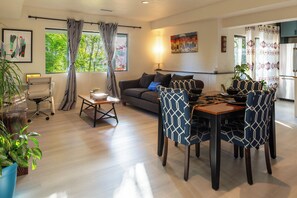 Un salon moderne avec un canapé, une table à manger, des chaises et une cuisine en arrière-plan.