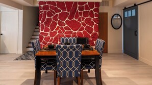 A dining area with a table, chairs, and a red textured wall.