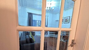 Een kamer met een groot raam, een deur en uitzicht op een zithoek met een bank en een tafel.
