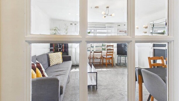 Un salon moderne comprenant un canapé, des fauteuils, une table basse et un coin repas avec des chaises et une table.