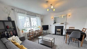 Un salon moderne comprenant un canapé, une table basse, un téléviseur, une cheminée et un coin repas.