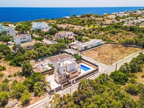 An aerial view of a coastal residential area with houses, a swimming pool, and a clear view of the sea. - Garlanda by Interhome (Llombards/C.Llombards/C.S'Almonia)