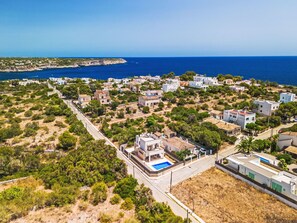 A coastal residential area with houses, a road, and a clear view of the sea. - Garlanda by Interhome (Llombards/C.Llombards/C.S'Almonia)