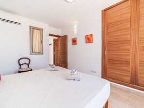 Ein Hotelzimmer mit einem Bett, einem Holzschrank, einem Sessel und einem Fenster mit Vorhängen.