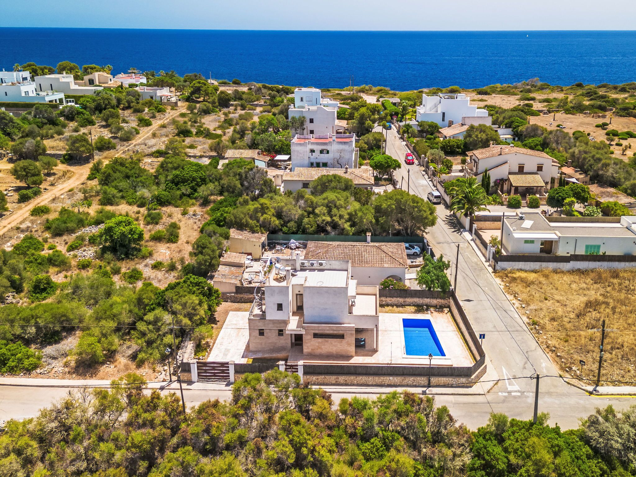 Vista aérea de una zona residencial costera con casas, piscina y una vista despejada del mar.