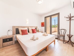 A bedroom with a bed, bedside tables, a chair, and a coat rack. - Garlanda by Interhome (Llombards/C.Llombards/C.S'Almonia)