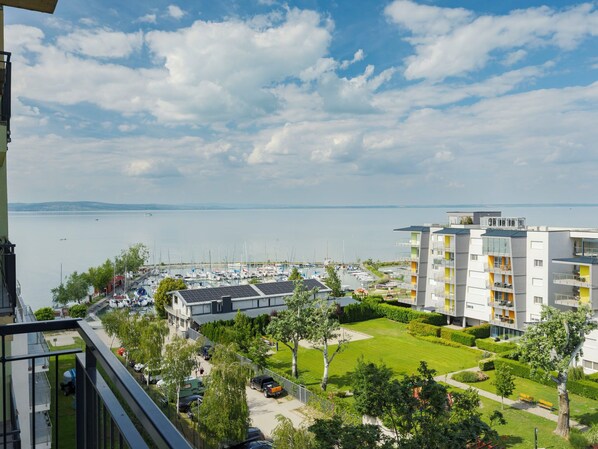 Un moderno edificio de apartamentos con balcones, un puerto deportivo con barcos y vistas al agua.