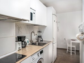 A compact kitchen with a built-in oven, a coffee maker, a blender, and a washing machine. - Las Naciones by Interhome (Benalmádena Costa)
