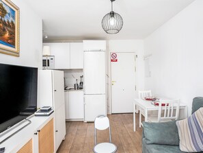 Um espaço compacto com cozinha compacta, área de refeições e televisão.