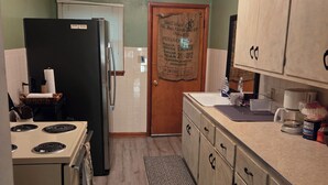 A compact kitchen with a refrigerator, stove, and wooden cabinets.