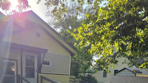 A wooden deck leading to a house with a gravel path and a flower pot on a pedestal.