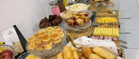 Ein reichhaltiges Buffet mit verschiedenen Speisen, darunter Gebäck, Früchte und Getränke.