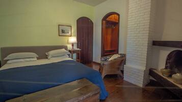 Um quarto com cama, poltrona, luminária e lareira.