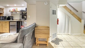 A compact living space with a kitchenette, a sofa, a small wooden table, and a staircase. - Work, Play & Explore w/ Ease! Dtwn Meridian Apt (Meridian)
