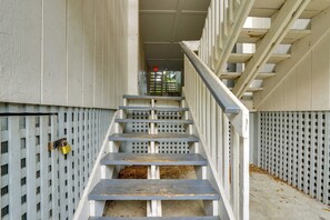 A staircase with a metal railing, leading to an exit door with a red emergency light. - 1 Mi to Beach! HHI Extended Escape w/ Balcony (Hilton Head Island)