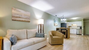 Un salon comprenant un canapé, un fauteuil et un coin repas avec une table et des chaises.
