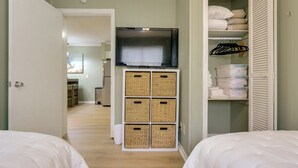 Une chambre avec deux lits, un téléviseur posé sur un meuble et une armoire avec des compartiments de rangement.